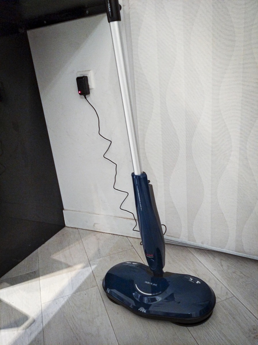 Mop stojący tuż przy gniazdku, krótki kabel zasilacza sięga od ściany do gniazda nad stopką